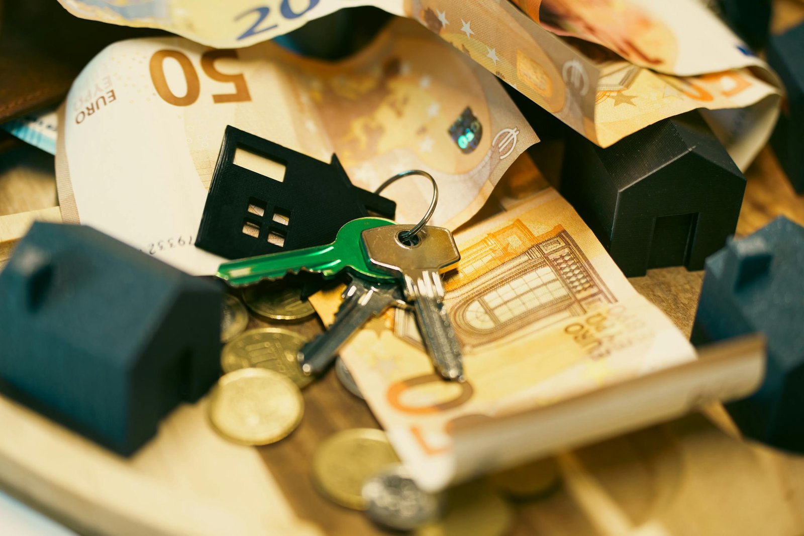Euro currency with house keys and miniature models, symbolizing real estate investment.